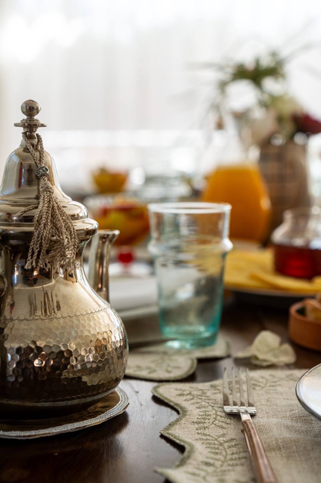 Moroccan breakfast table with a silver teapot, mint tea glass and fresh orange juice
